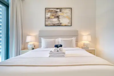 a bedroom with a large white bed with two lamps at Luxury 2-Bed Apartment l Emaar Beachfront in Dubai