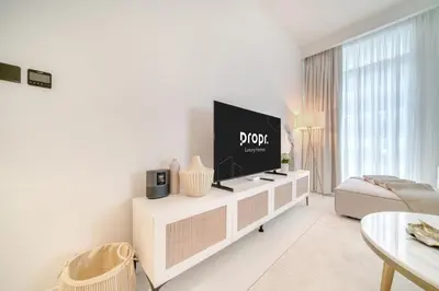 a living room with a flat screen tv on a white cabinet at Luxury 2-Bed Apartment l Emaar Beachfront in Dubai