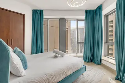 a bedroom with a large bed with blue curtains at Bellavista - 29 BLVD - 1 Bedroom Burj Khalifa & Fountain View in Dubai
