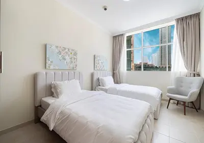 a bedroom with two beds and a chair and a window at lux 2BD in heart of Downtown, 2 Mins Walk to Dubai Mall - Burj al Nujoom in Dubai