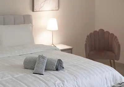 a bedroom with a bed with a pillow and a chair at lux 2BD in heart of Downtown, 2 Mins Walk to Dubai Mall - Burj al Nujoom in Dubai