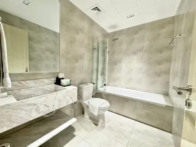 a bathroom with a toilet and a tub and a sink at Urban Oasis Stylish JLT Apartment with Lake Views in Dubai
