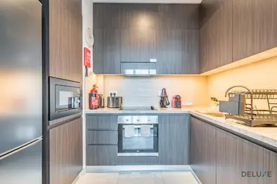 a kitchen with wooden cabinets and a stove top oven at Charming 1BR Apartment in Downtown Views 1, Downtown Dubai by Deluxe Holiday Homes in Dubai