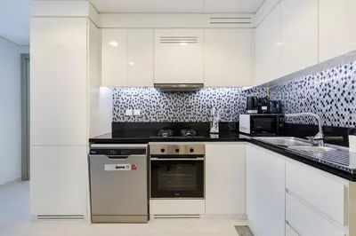 a white kitchen with a stove and a sink at ALiving Charming 1BR I Aykon City Tower, Business Bay in Dubai