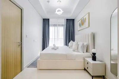 a white bedroom with a bed and a window at ALiving Charming 1BR I Aykon City Tower, Business Bay in Dubai