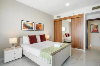 a bedroom with a large white bed with red pillows at Sky Haven in 45th Floor 2BR with Dubai Harbour Views in Dubai