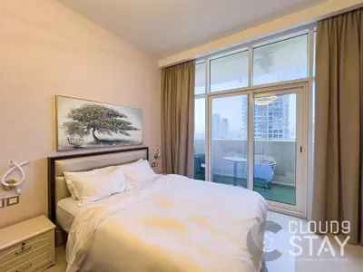 a bedroom with a bed and a large window at Cloud 9 - DAMAC Ghalia Tower in Dubai