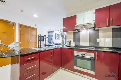 a kitchen with red cabinets and stainless steel appliances at Charming 1BR Apartment at Ocean Heights Dubai Marina by Deluxe Holiday Homes in Dubai
