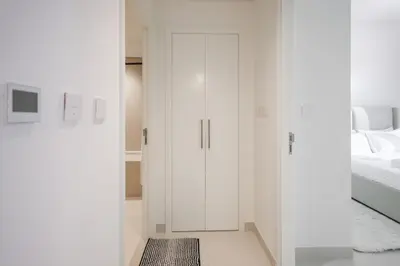 a white bedroom with a bed and a white cabinet at Downtown Apartments - Burj Crown - 5 Min Walk to Mall in Dubai