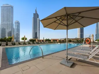 a pool with an umbrella and chairs and buildings at Sea & City Views - Burj Crown - 5 Min Walk to Mall in Dubai