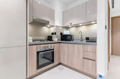 a kitchen with white cabinets and a stove top oven at FIRST CLASS Luxury 1BR plus Bunk Room in Sobha Waves, Close to Downtown Dubai in Dubai