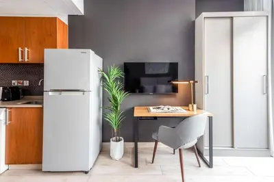 a kitchen with a refrigerator and a table with a plant at Silkhaus Burj Khalifa View Studio in Iconic Tower in Dubai