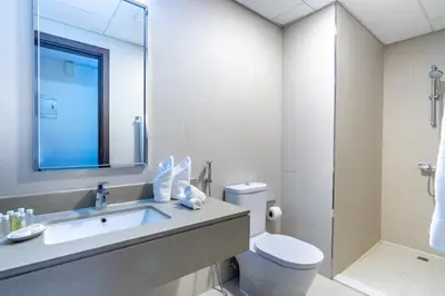 a bathroom with a sink and a toilet and a mirror at Silkhaus Modern Studio with Balcony in Burj Daman in Dubai