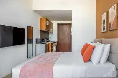 a bedroom with a large white bed with orange pillows at Silkhaus Spacious Studio in Heart of DIFC in Dubai