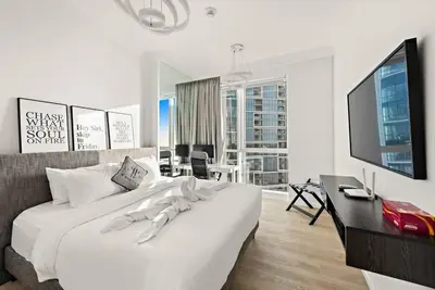 a white bedroom with a large bed and a desk at FIRST CLASS 2BR Vibrant Waterfront District in Dubai