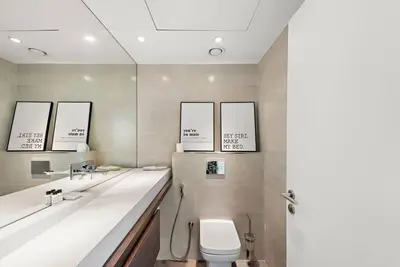 a bathroom with a toilet and two sinks and mirrors at FIRST CLASS 2BR Vibrant Waterfront District in Dubai