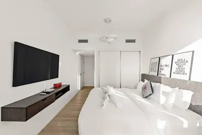 a white bedroom with a tv and a bed at FIRST CLASS 2BR Vibrant Waterfront District in Dubai