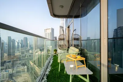a balcony with chairs and a table on top of a building at Sky-High Oasis with Burj Khalifa Views, Rooftop Infinity Pool, 3BR Apartment in Paramount Hotel Midtown in Dubai