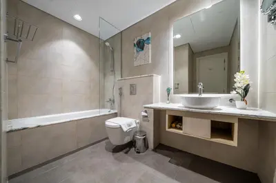 a bathroom with a sink and a tub and a toilet at Sky-High Oasis with Burj Khalifa Views, Rooftop Infinity Pool, 3BR Apartment in Paramount Hotel Midtown in Dubai