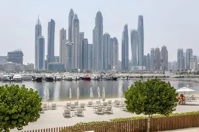 a harbor with tables and chairs and a city skyline at Frank Porter - Marina Vista Podium 3 in Dubai