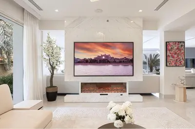 a living room with a fireplace with a tv above it at JuliusHomes - 5BR Villa with Pool in Palm Jumeirah in Dubai