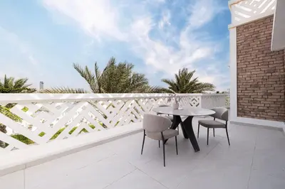 a patio with a table and chairs on a white fence at JuliusHomes - 5BR Villa with Pool in Palm Jumeirah in Dubai