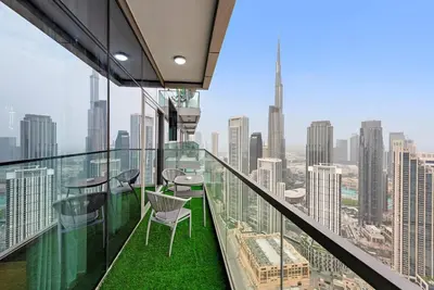 a balcony with chairs and tables on top of a building at FIRST CLASS 2BR Luxurious High-Floor Suite in Dubai