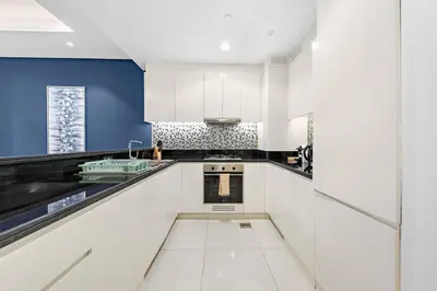 a kitchen with white cabinets and blue walls at FIRST CLASS 2BR Luxurious High-Floor Suite in Dubai