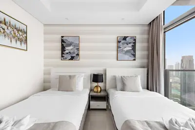 two beds in a room with a window at FIRST CLASS 2BR Luxurious High-Floor Suite in Dubai