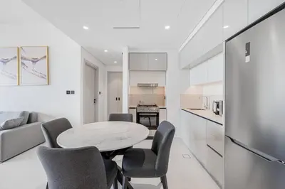 a kitchen and living room with a table and chairs at Fully Equipped 1BR with Private Beach Access in Dubai