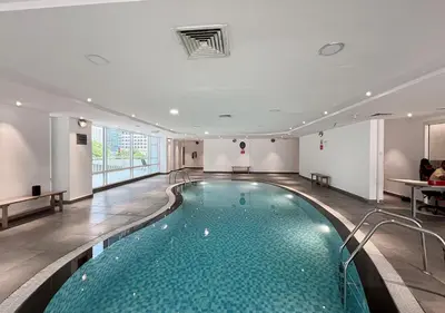 a swimming pool in a hotel with people sitting on tables at Lux Studio in JLT with Amazing View Next to the Metro - Dubai Arch tower in Dubai