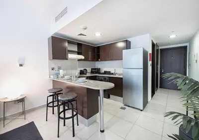 a kitchen with a refrigerator and some bar stools at Lux Studio in JLT with Amazing View Next to the Metro - Dubai Arch tower in Dubai
