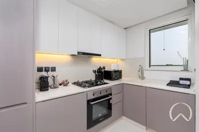 a kitchen with white cabinets and a stove top oven at Oraya - Upgraded 2BR In Prive Maison, Central Canal View in Dubai