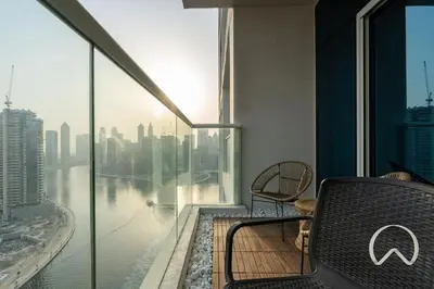 a room with a balcony with a view of a city at Oraya - Upgraded 2BR In Prive Maison, Central Canal View in Dubai
