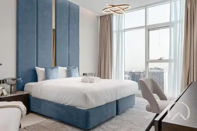 a bedroom with a large bed with a blue wall at Oraya - Upgraded 2BR In Prive Maison, Central Canal View in Dubai