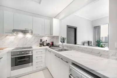 a white kitchen with white cabinets and a sink at Daniels 1BR at Silverene Tower Dubai Marina in Dubai