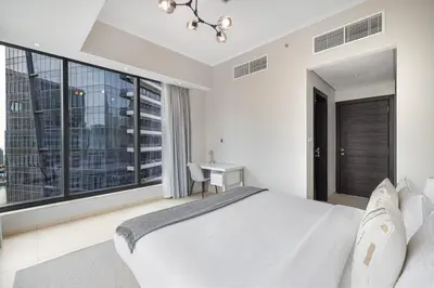 a bedroom with a large white bed and a desk at Daniels 1BR at Silverene Tower Dubai Marina in Dubai