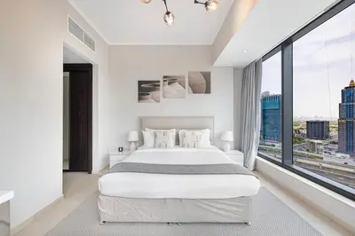 a white bedroom with a large bed and large windows at Daniels 1BR at Silverene Tower Dubai Marina in Dubai