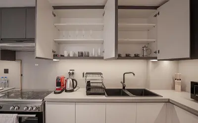 a kitchen with white cabinets and a sink at Modern JVC 1BR with Spacious Terrace in Dubai