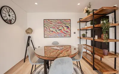 a dining room with a table and chairs and a clock at Modern JVC 1BR with Spacious Terrace in Dubai