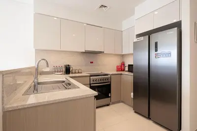 a kitchen with a stainless steel refrigerator and a sink at 5 Minute Walk to The Fountains! Full Burj Khalifa View! 5-star Pool & Gym! in Dubai