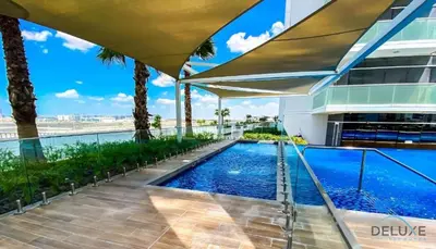 a swimming pool on the roof of a building with palm trees at Inviting Studio in Damac Hills Carson B, Dubailand by Deluxe Holiday Homes in Dubai