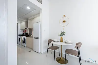 a white kitchen with a white table and chairs at Inviting Studio in Damac Hills Carson B, Dubailand by Deluxe Holiday Homes in Dubai