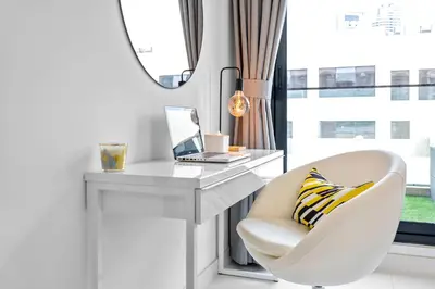 a white desk with a chair and a laptop at Premium Studio Apartment at Loci Residences JVC in Dubai