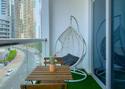 a swing on a balcony with a table and a cactus at First Line Canal View Studio with Balcony MAX 4 Pax in Dubai