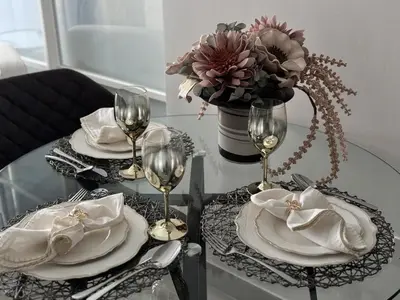a table with two plates and wine glasses on it at Chic 1 BR apartment at Golfville in Dubai