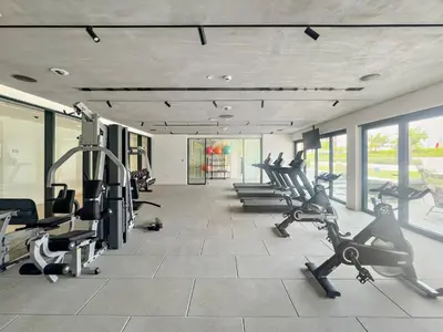 a gym with several treadmills and cardio machines at Chic 1 BR apartment at Golfville in Dubai