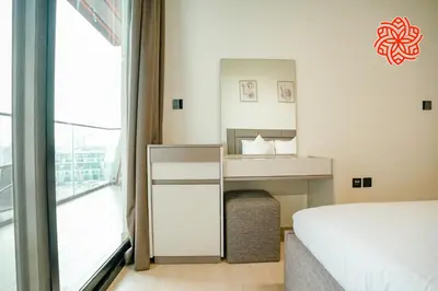 a bedroom with a bed and a desk and a window at Alashrafia Saray - Bright 1bdr apartment in JVC in Dubai