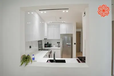 a kitchen with white cabinets and a stainless steel refrigerator at Alashrafia Saray - Bright 1bdr apartment in JVC in Dubai