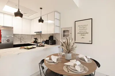 a kitchen with a wooden table with chairs and a counter at Brand New 1BR with Pool, Sauna & Gym in Dubai